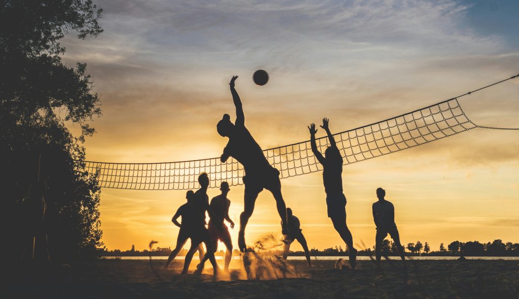 Corporate group playing beach volleyball for a team building event.